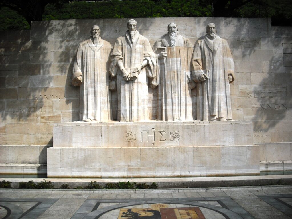 Reformation Wall, Geneva Switzerland. The figures depict the four great preachers: Guillaume Farel, Jean Calvin, Théodore de Bèze and John Knox, all four wearing the ‘robe of Geneva’ and holding the little people’s bible.